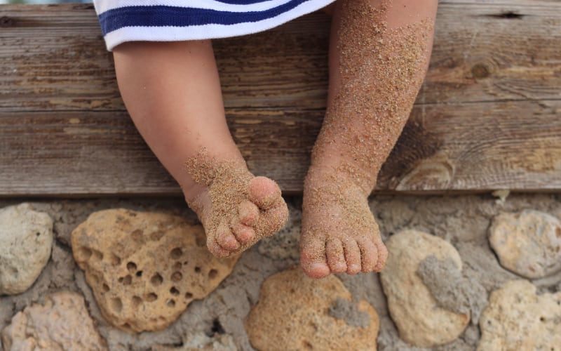 Child with sand covered legs at the beach